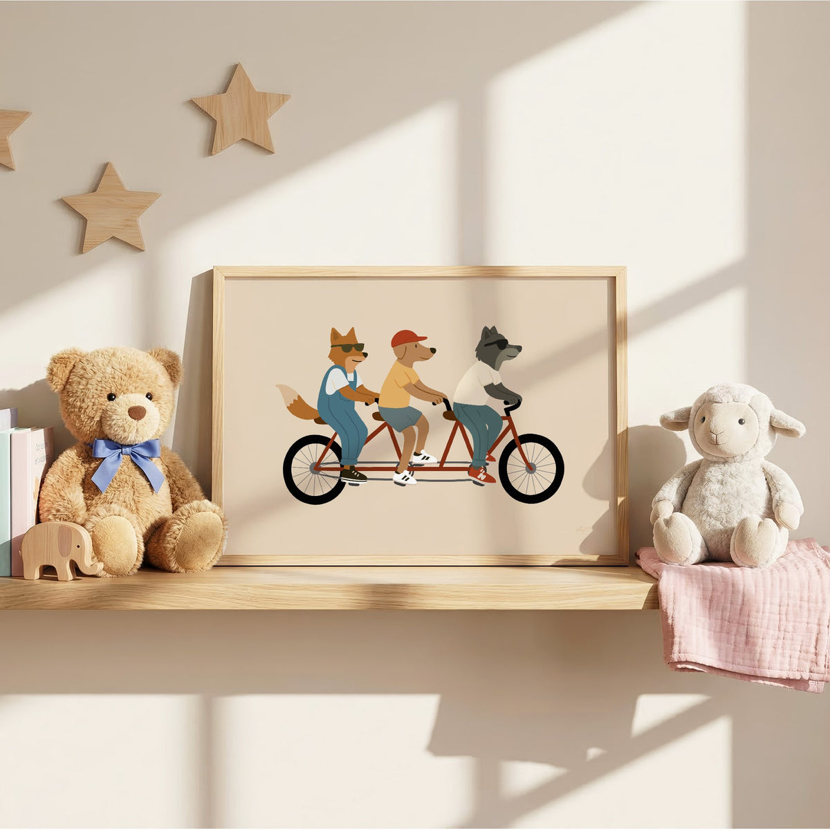 Animal friends riding tandem bike nursery print in an oak frame on a wall shelf between a teddy bear and a toy lamb