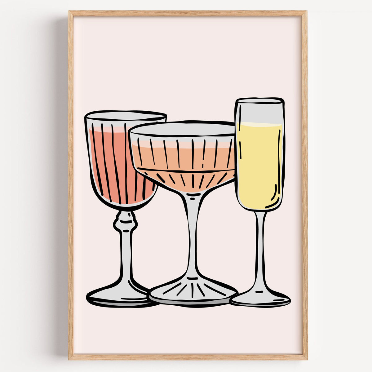 Three pastel cocktail glasses and champagne flute print in a light oak frame on a plain white wall