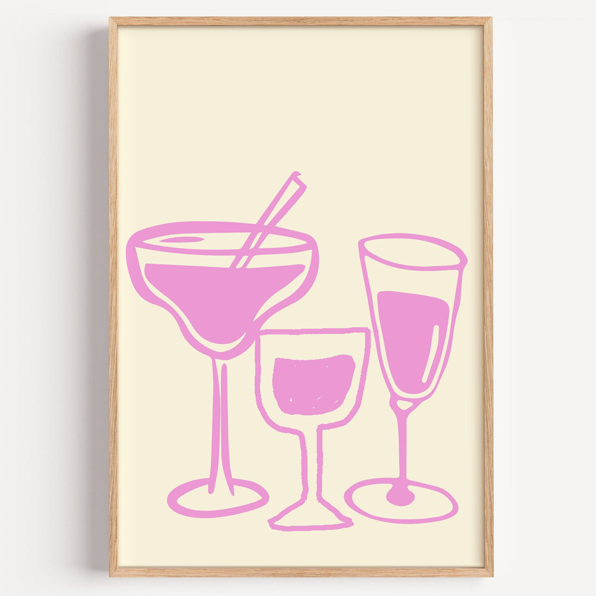 Three pink cocktail glasses linocut-style print in a light oak frame on a plain white wall