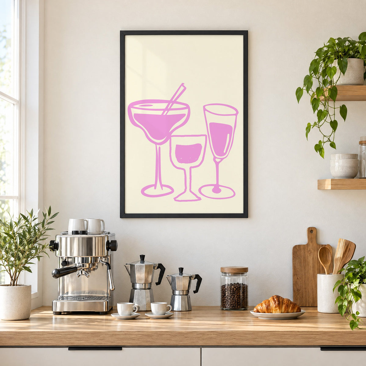 Three pink cocktail glasses linocut-style print in a black frame above a home espresso bar with moka pots and espresso cups