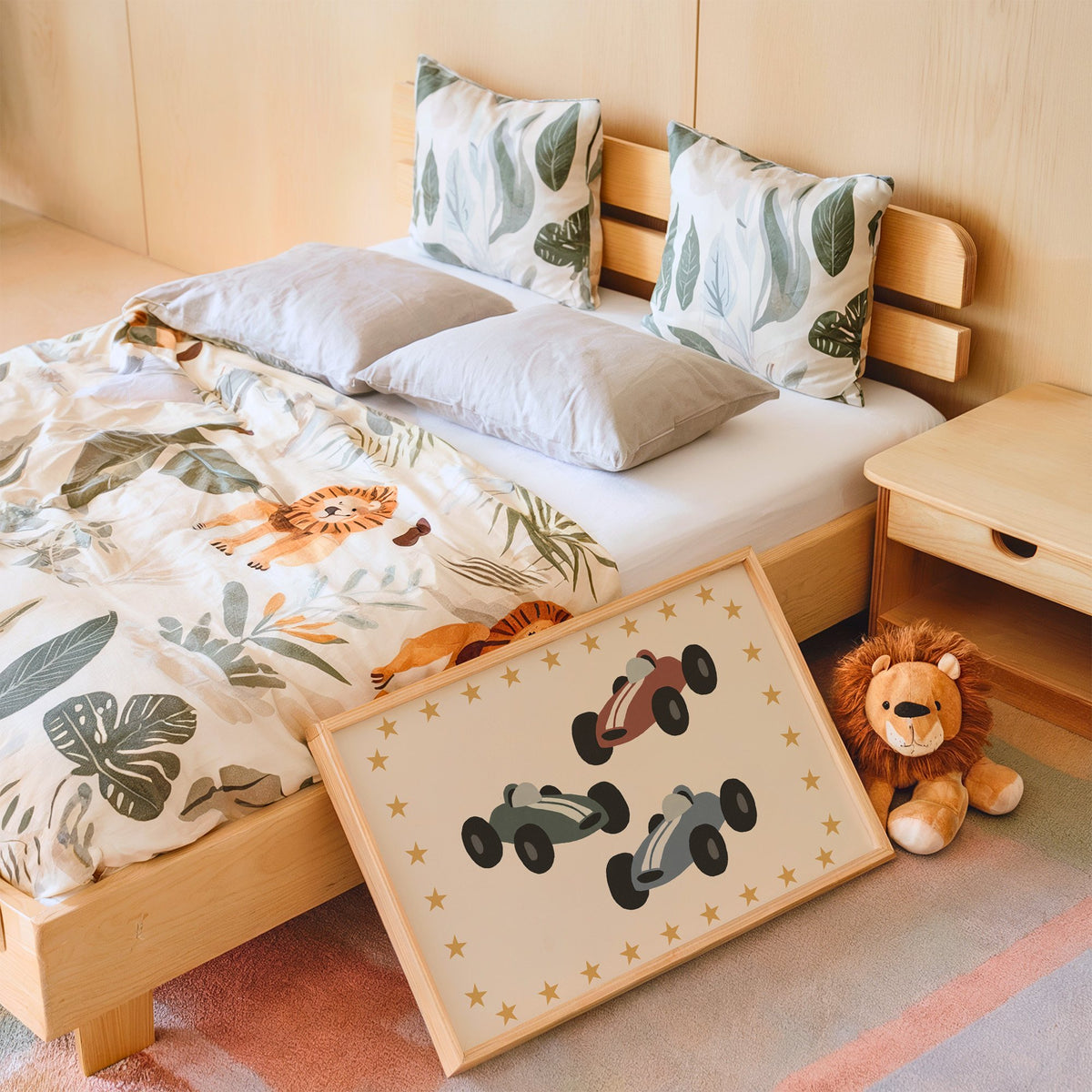 Landscape three race cars star border nursery print in an oak frame leaning on a kids bed by a lion plush