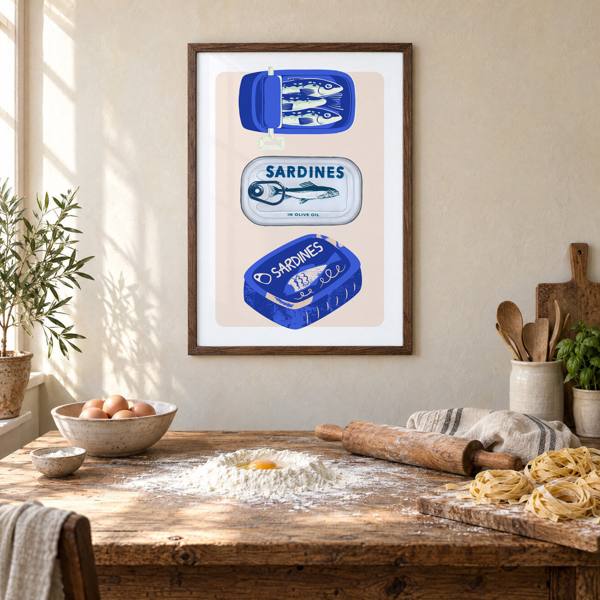 Three sardine tins cobalt print in a walnut frame above a rustic table set for making fresh pasta
