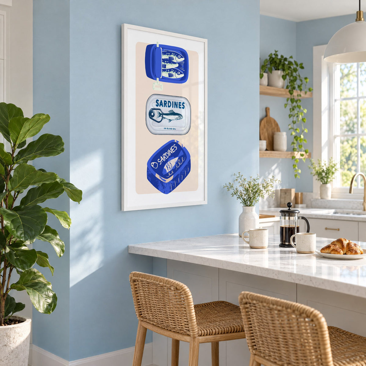 Three sardine tins cobalt print in a white frame on a pale blue wall above a breakfast bar with rattan stools