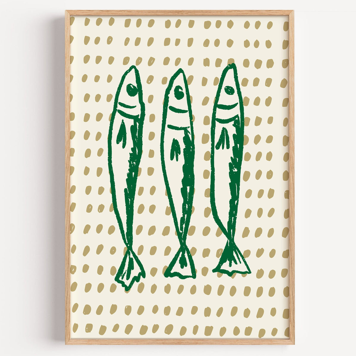 Three green sardines on dotted print in a light oak frame on a plain white wall