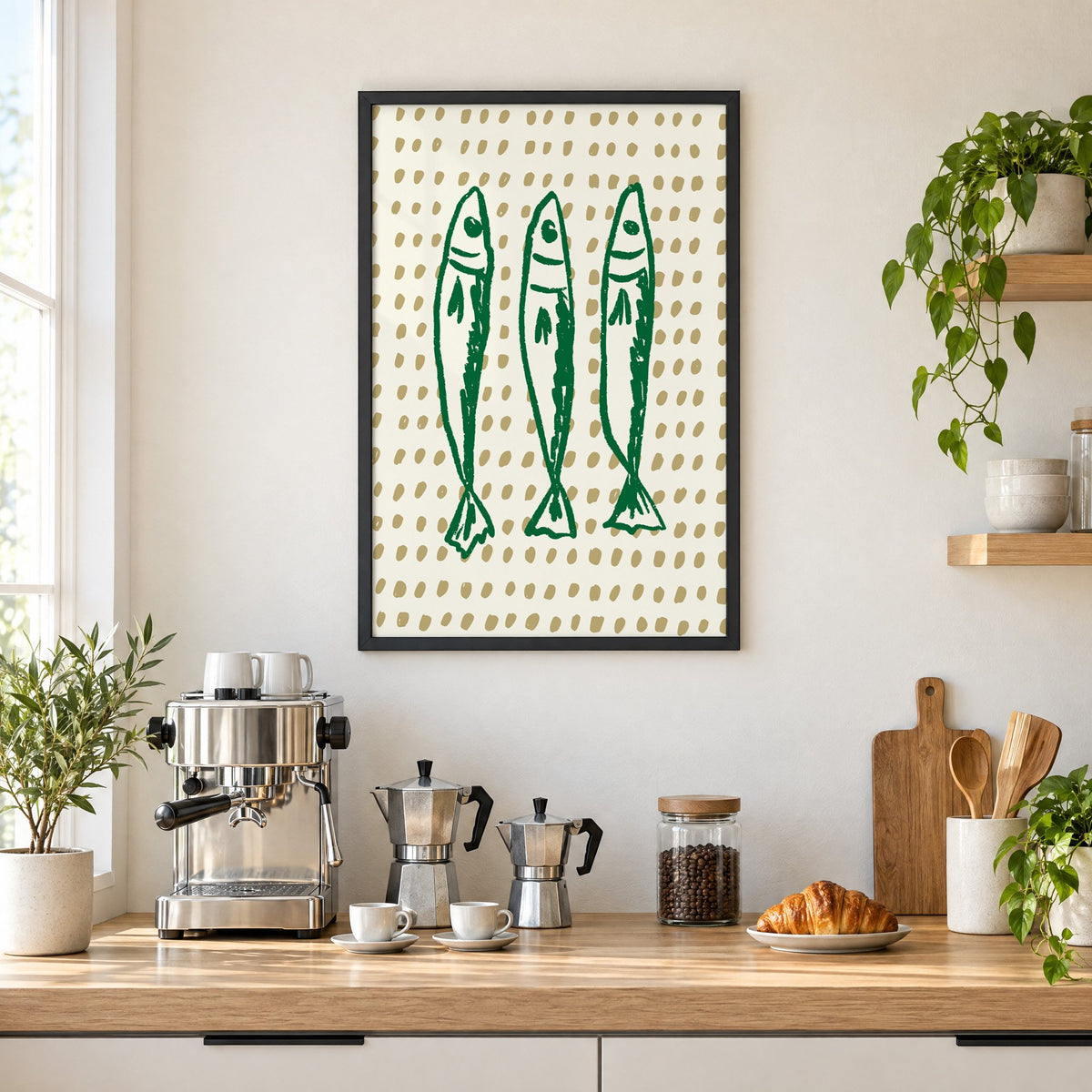 Three green sardines on dotted print in a black frame above a home espresso bar with moka pots and espresso cups