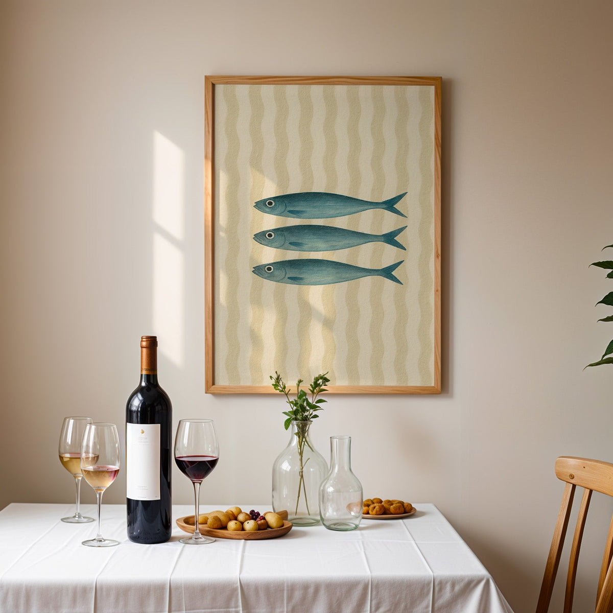 Three vintage sardines print in an oak frame above a table laid with red wine
