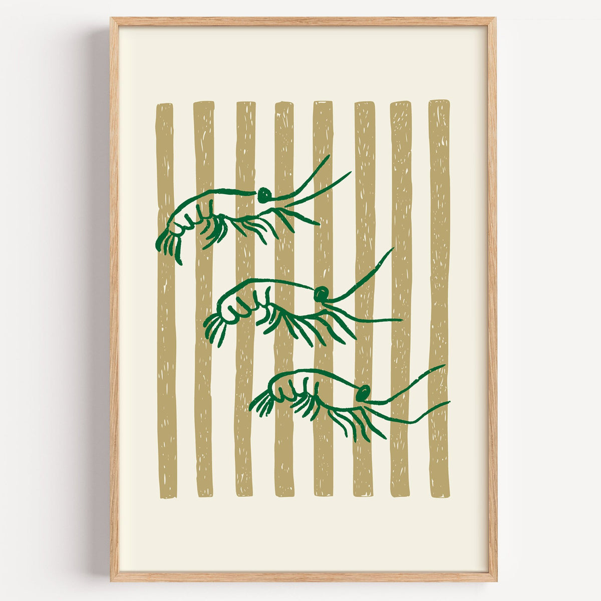 Three green shrimp on gold stripes print in a light oak frame on a plain white wall