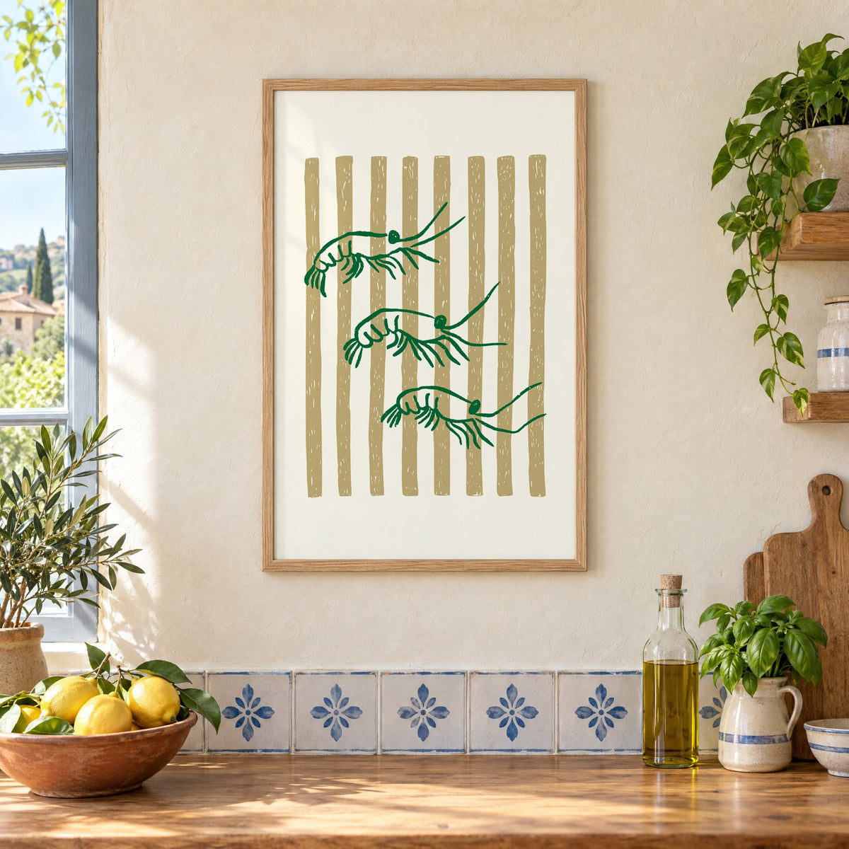 Three green shrimp on gold stripes print in an oak frame on a cream plaster wall above a worktop with a bowl of lemons and blue-and-white tiles