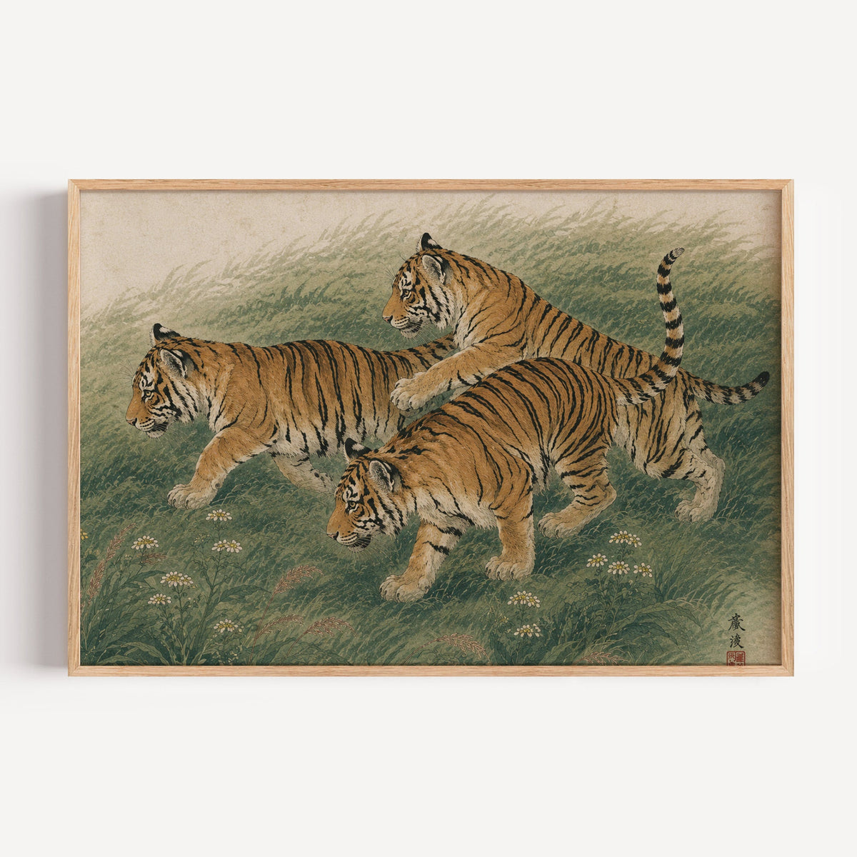 Three tiger cubs in tall grass print in a light oak frame on a plain white wall