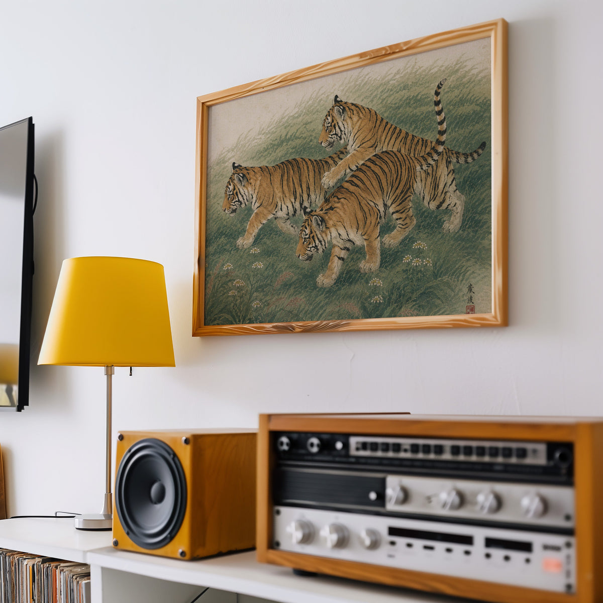 Three tiger cubs in tall grass print in a pine frame above a vintage stereo and a yellow table lamp