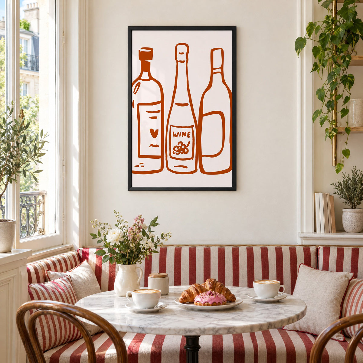 Three wine bottles rust brush line print in a black frame above a striped cafe breakfast nook with cappuccino and pastries