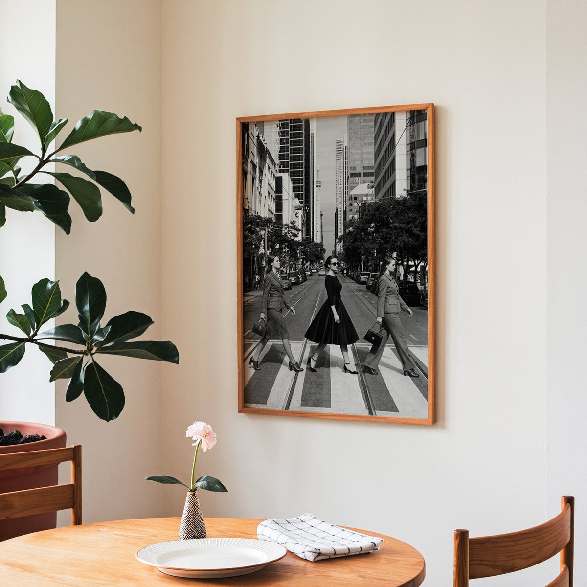 Three women crossing a city street print in a teak frame above a round wooden dining table