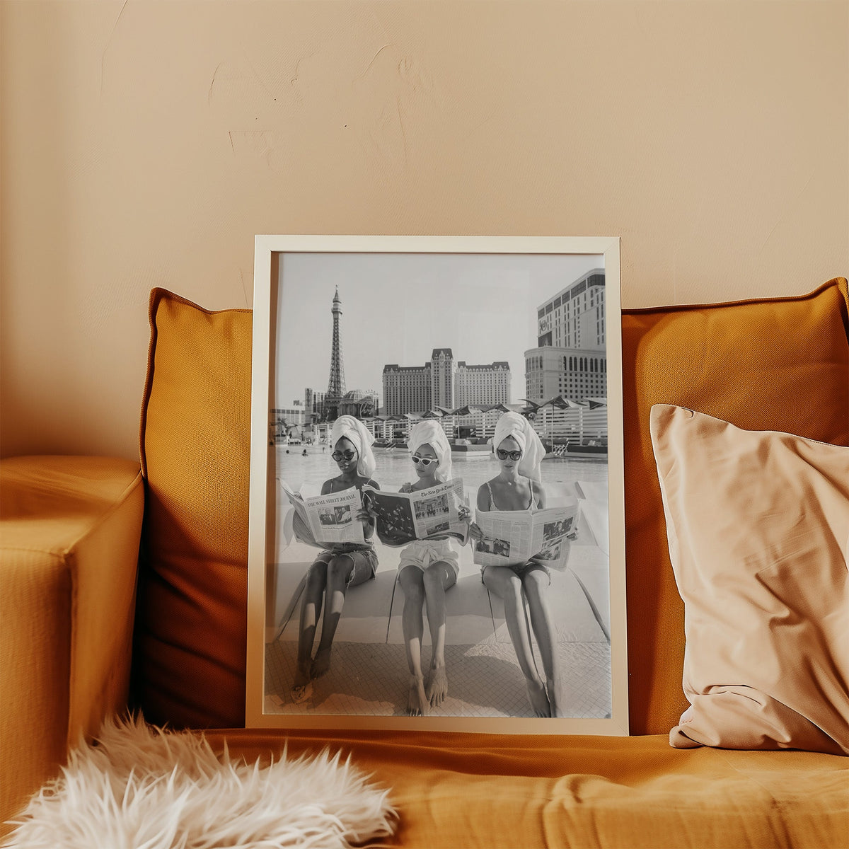 Three women in towel turbans reading newspapers print in a white frame leaning on a mustard velvet sofa