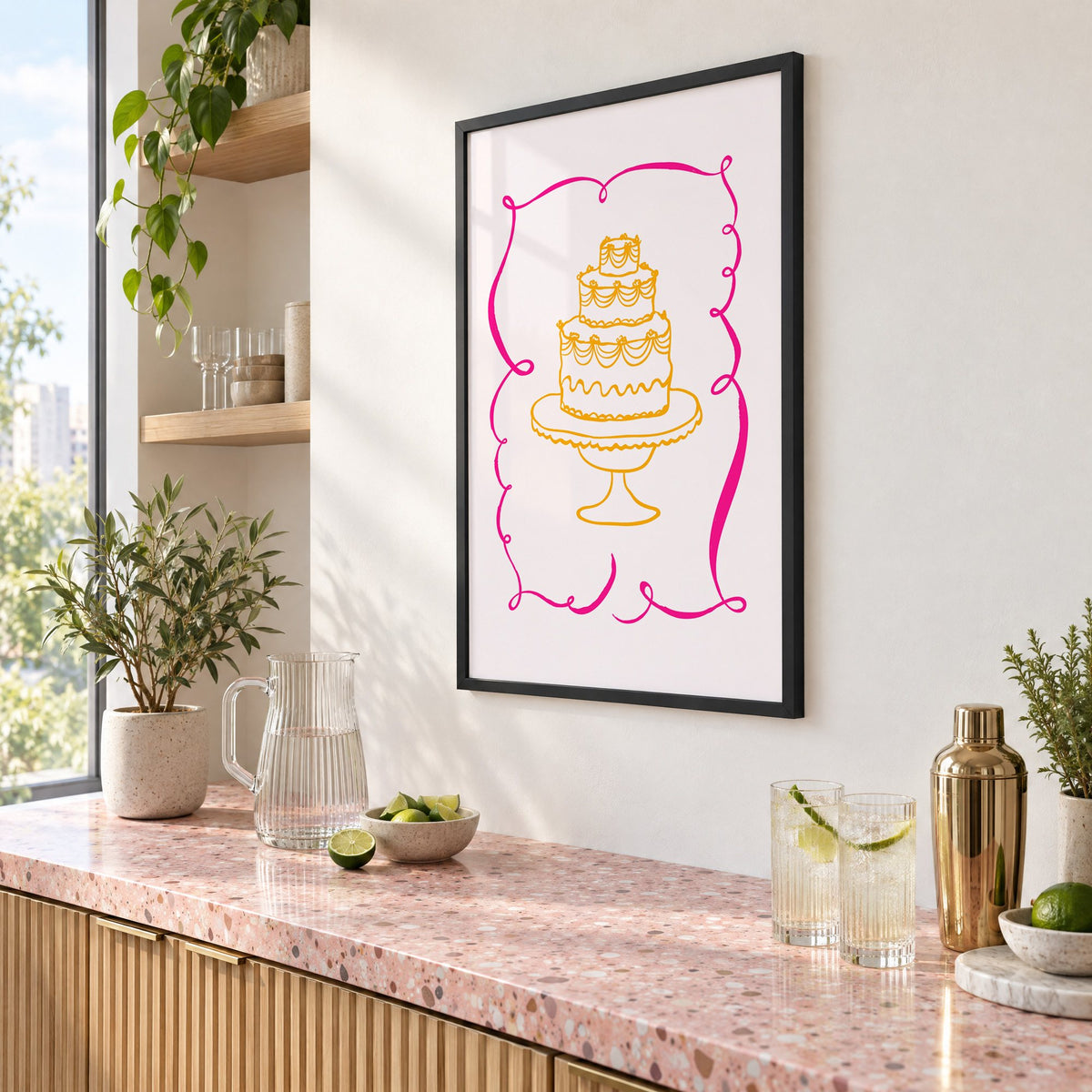 Tiered cake pink ribbon frame print in a black frame above a pink terrazzo cocktail counter with limes, seen at an angle
