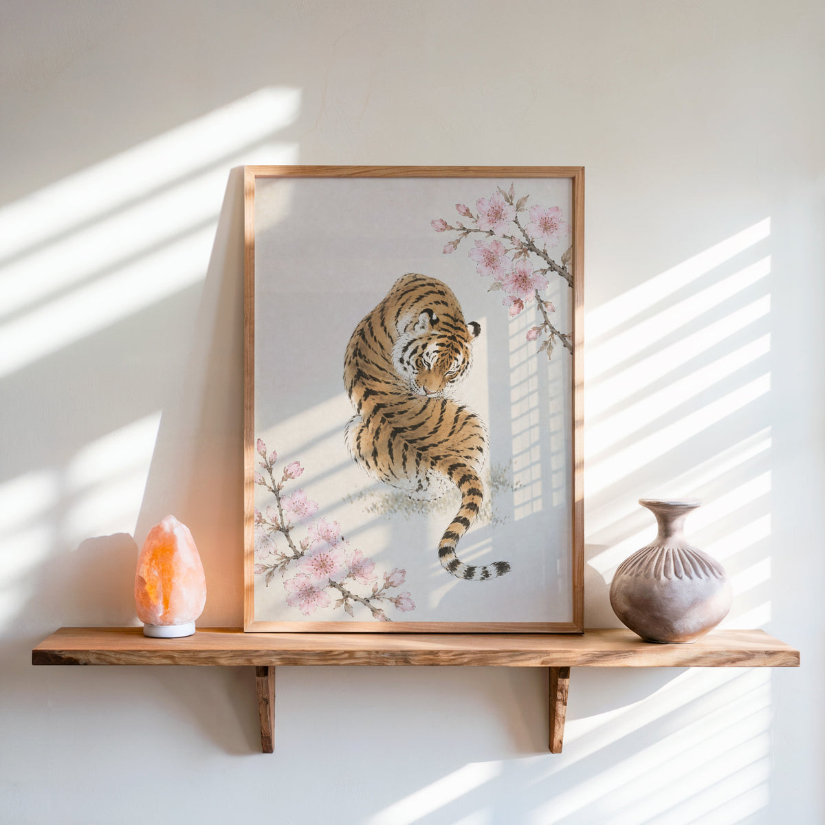 resting tiger with cherry blossom print in an oak frame on a live-edge wall shelf with a salt lamp and clay vase