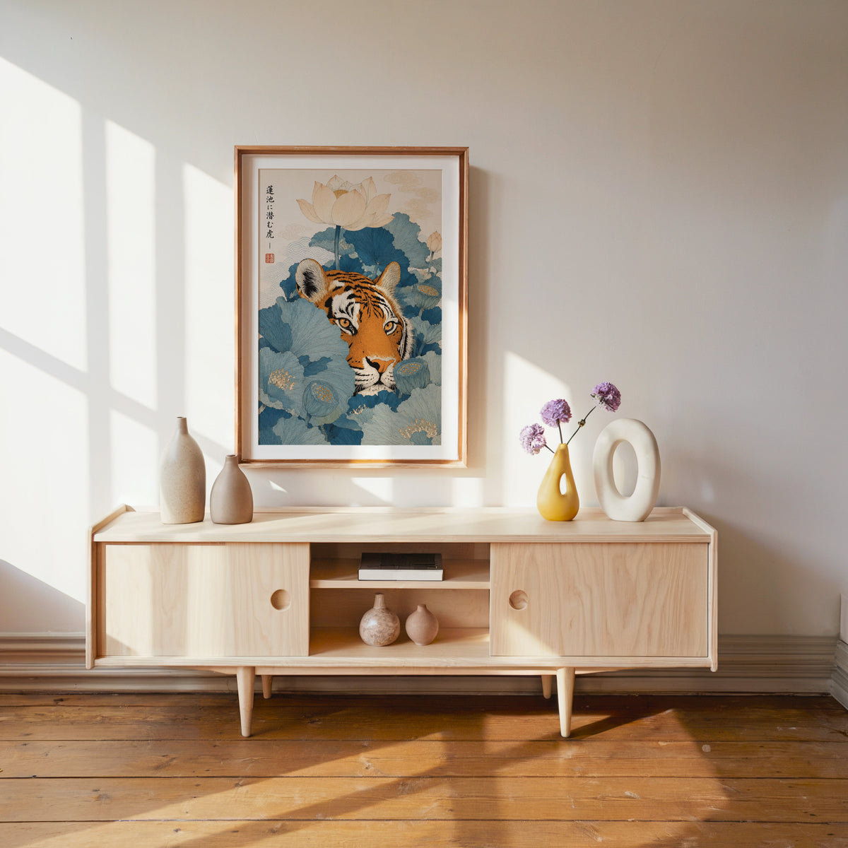 tiger hiding in blue lotus leaves print shown in a wood frame with a white mat above a pale wood media console