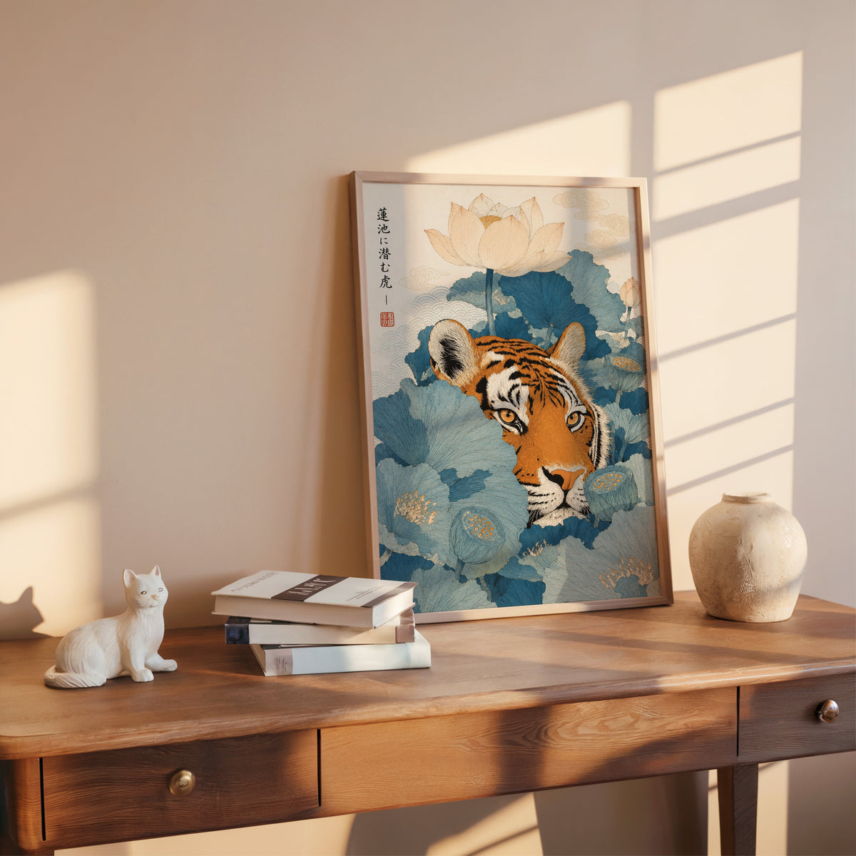 tiger hiding in blue lotus leaves print shown in a rose gold frame leaning on a wooden writing desk with books