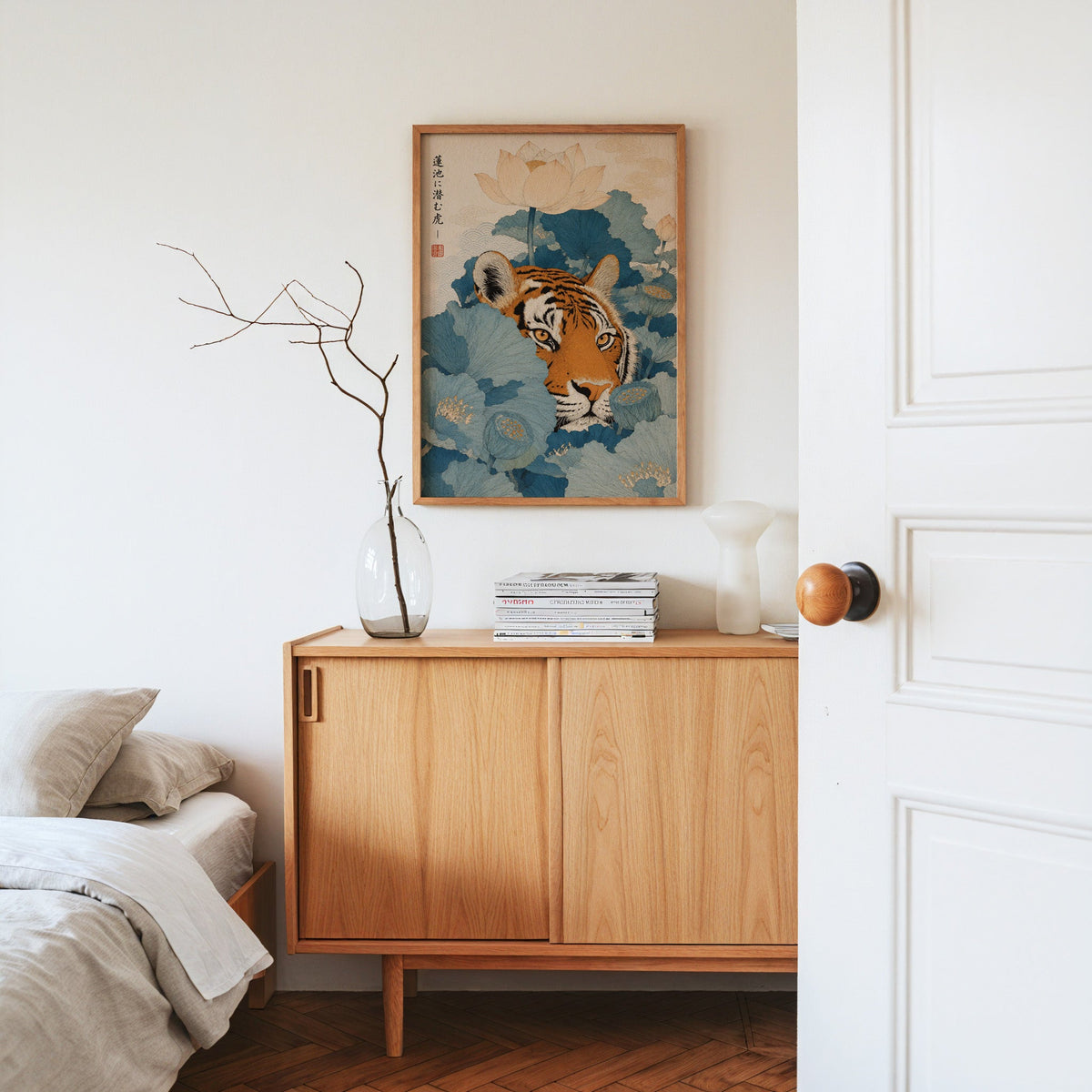 tiger hiding in blue lotus leaves print in an oak frame above an oak sideboard in a bedroom with linen bedding