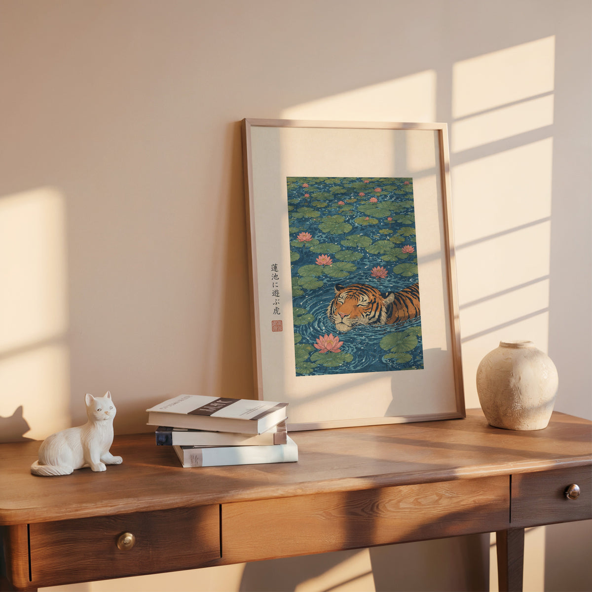 tiger swimming in lotus pond print shown in a rose gold frame leaning on a wooden writing desk with books