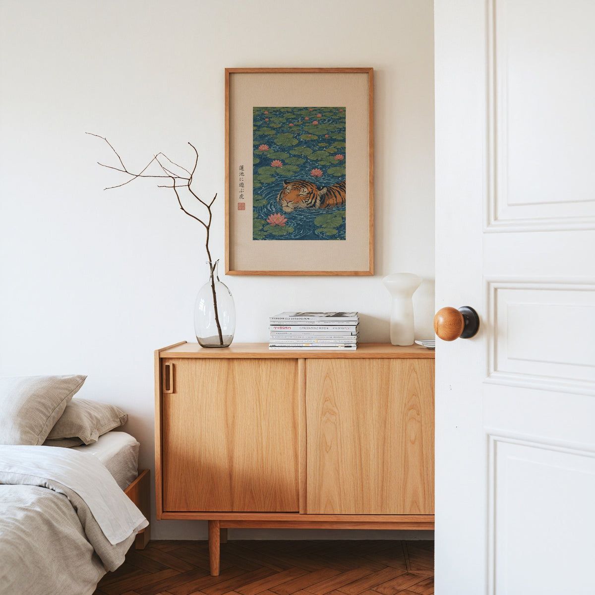 tiger swimming in lotus pond print in an oak frame above an oak sideboard in a bedroom with linen bedding