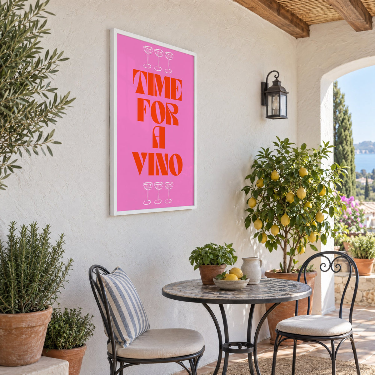Time for a Vino pink coupes print in a white frame on a sunny patio wall beside a potted lemon tree