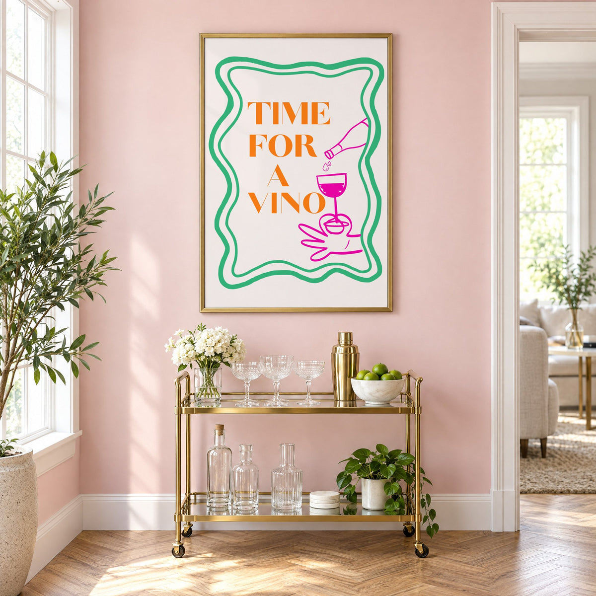 TIME FOR A VINO wine pour wavy frame print in a brass frame on a blush pink wall above a gold bar cart with glassware
