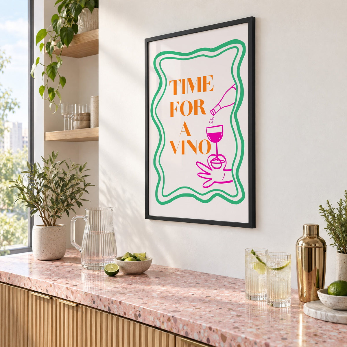 TIME FOR A VINO wine pour wavy frame print in a black frame above a pink terrazzo cocktail counter with limes, seen at an angle