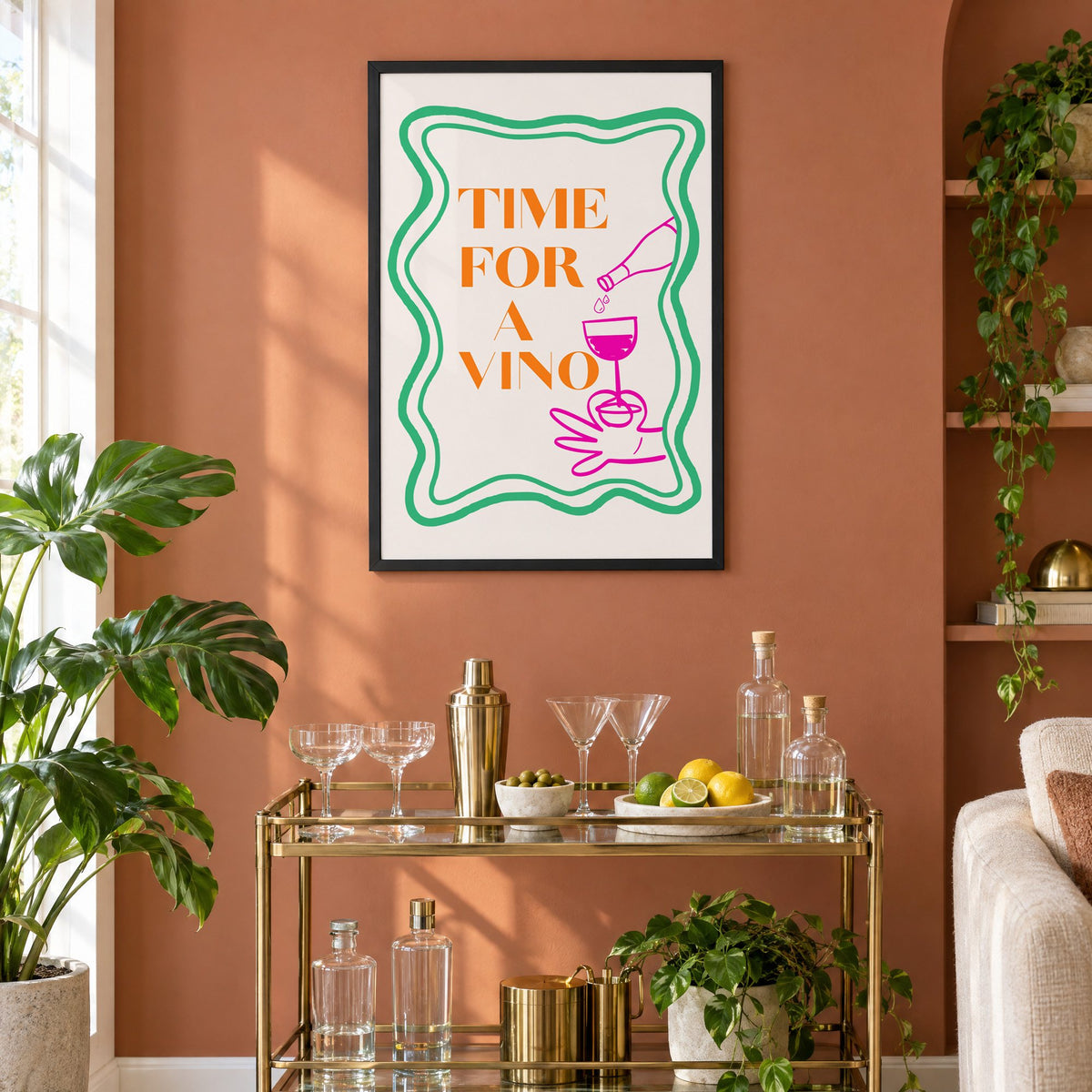 TIME FOR A VINO wine pour wavy frame print in a black frame on a terracotta wall above a brass bar cart with coupes and citrus