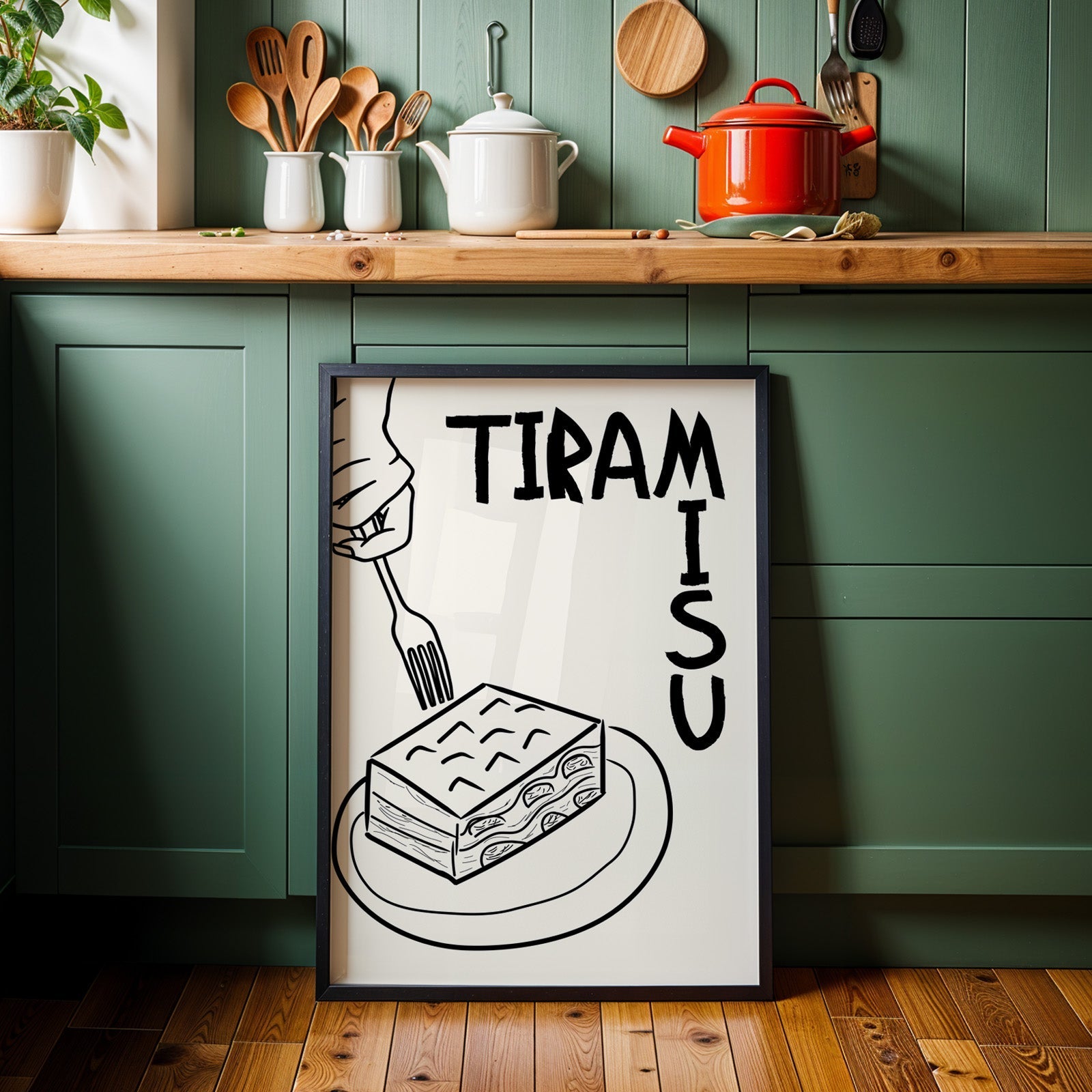 Tiramisu line art print in a black frame against sage green kitchen cabinets