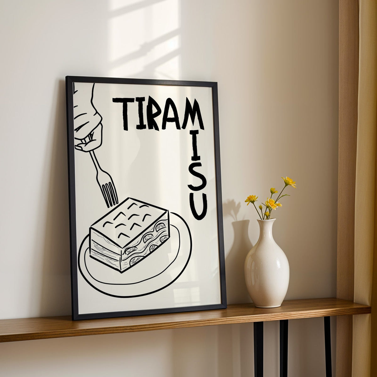 Tiramisu line art print in a black frame on a console table with yellow daisies