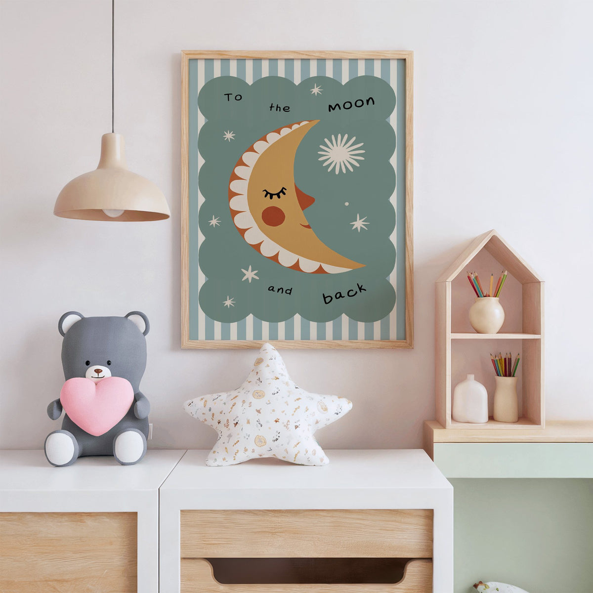 To the moon and back nursery print in an oak frame above a white dresser with a star pillow and house shelf