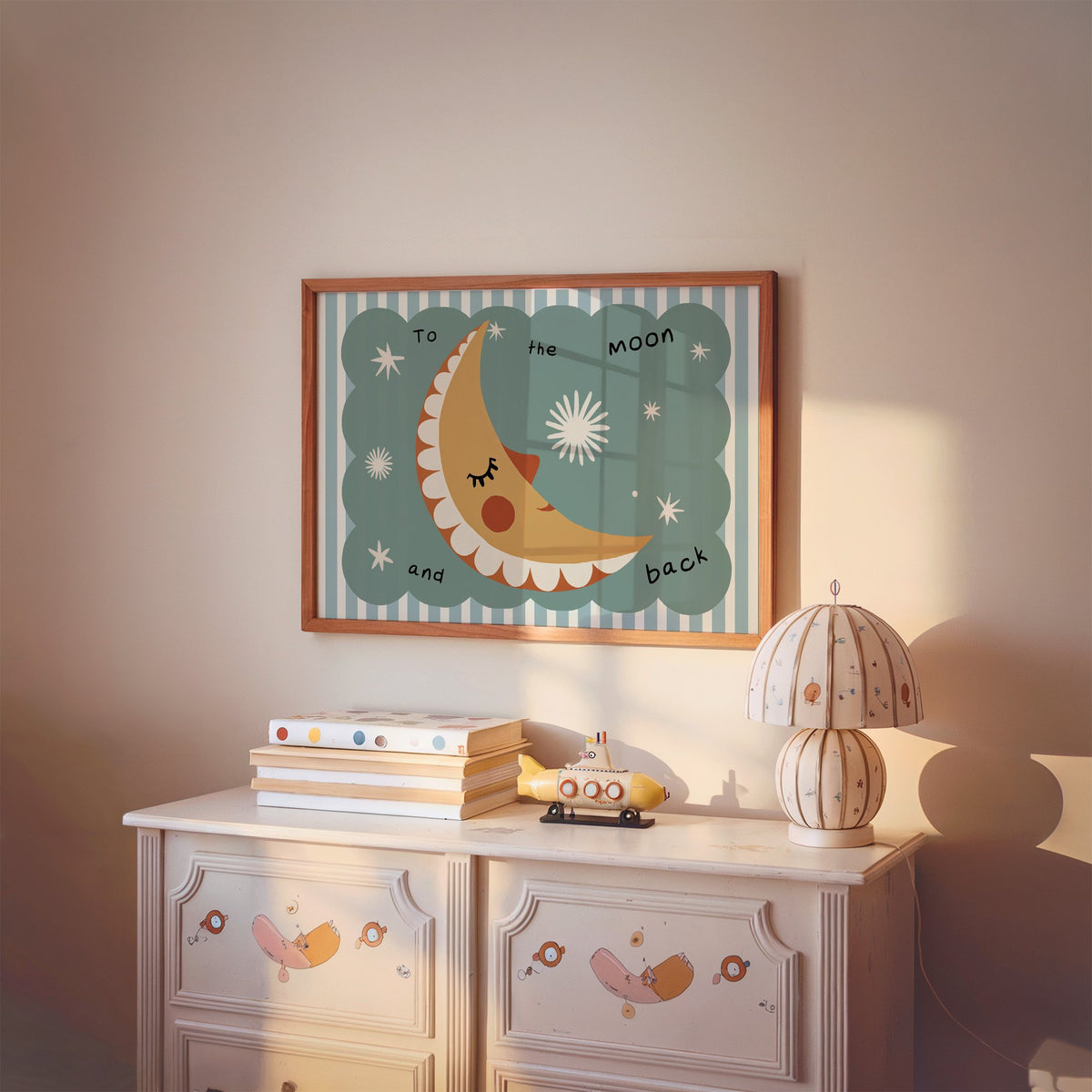 Landscape to the moon and back nursery print in a cherry wood frame above a painted dresser and lamp