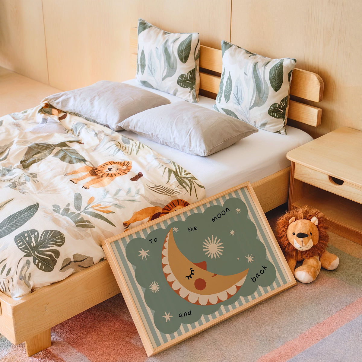 Landscape to the moon and back nursery print in an oak frame leaning on a kids bed by a lion plush