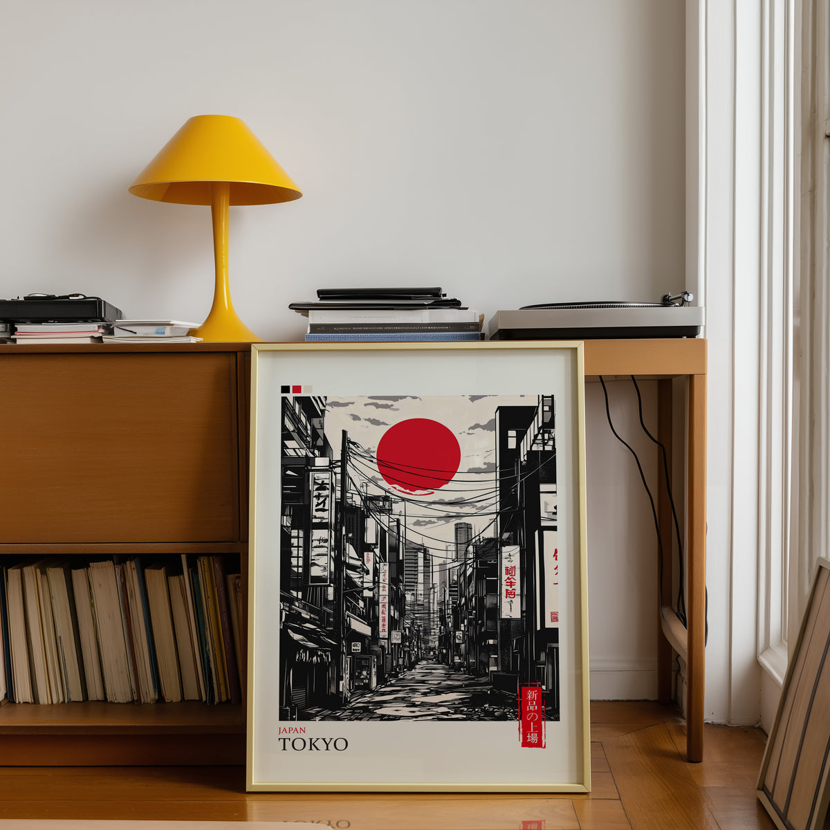 Tokyo ink street with red sun print shown in a gold frame below a teak desk with a yellow lamp