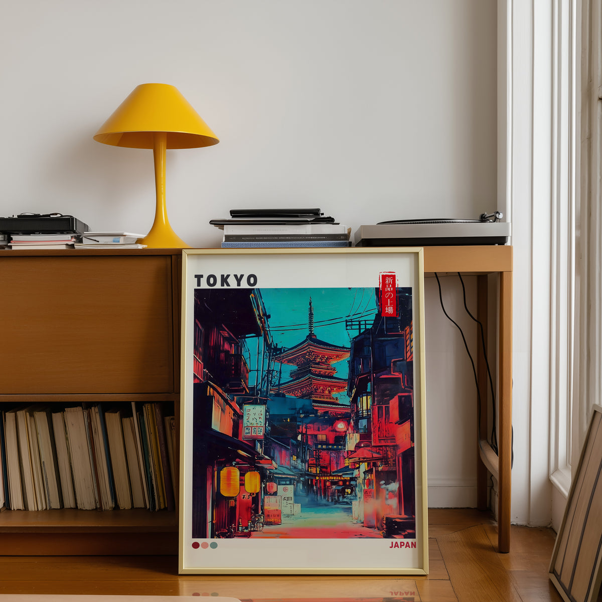 Tokyo neon alley and red pagoda print shown in a gold frame below a teak desk with a yellow lamp