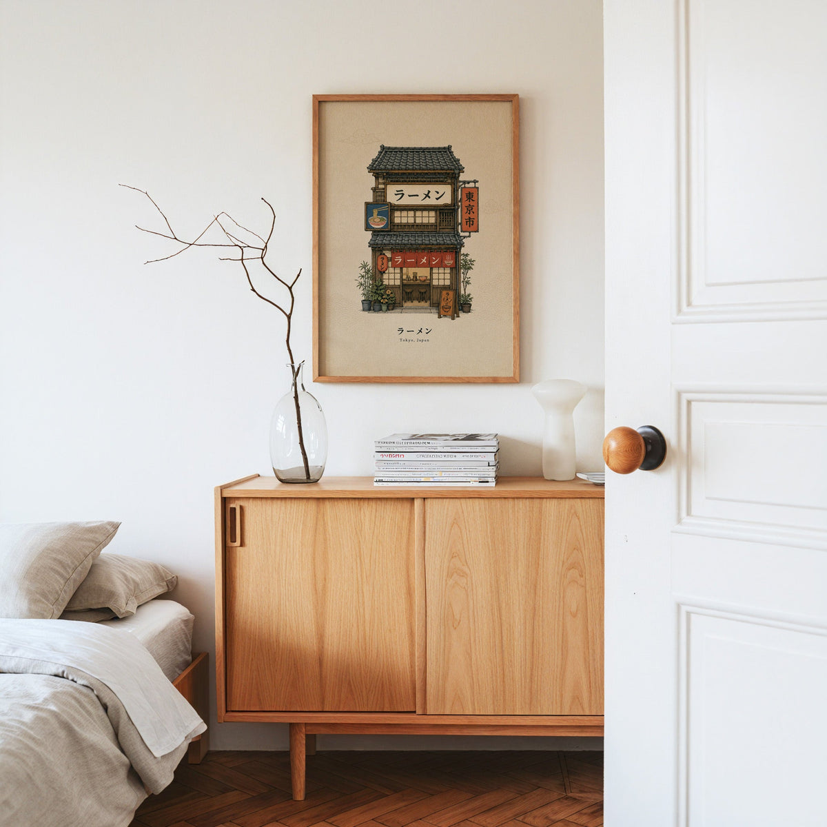 Tokyo ramen shop storefront print in an oak frame above an oak sideboard in a bedroom with linen bedding