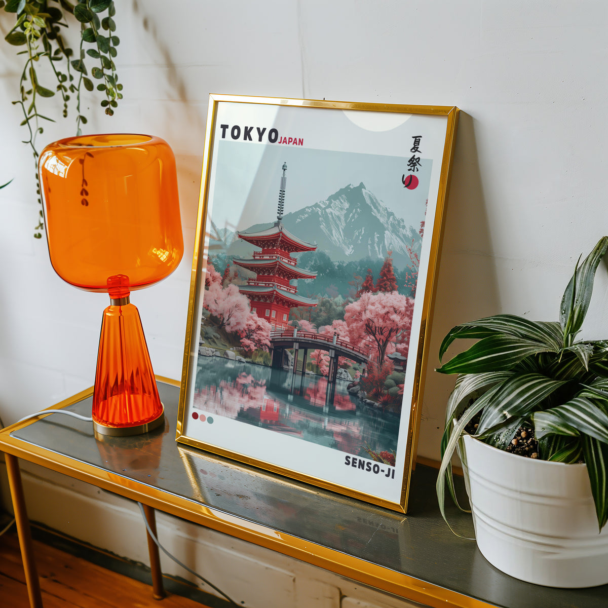 Red pagoda and arched bridge sakura print shown in a gold frame on a console beside an orange glass lamp