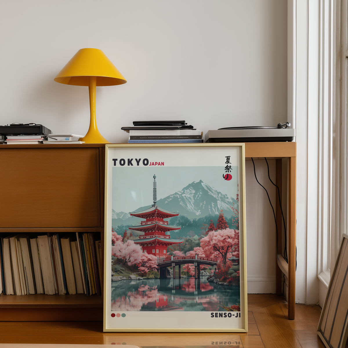 Red pagoda and arched bridge sakura print shown in a gold frame below a teak desk with a yellow lamp