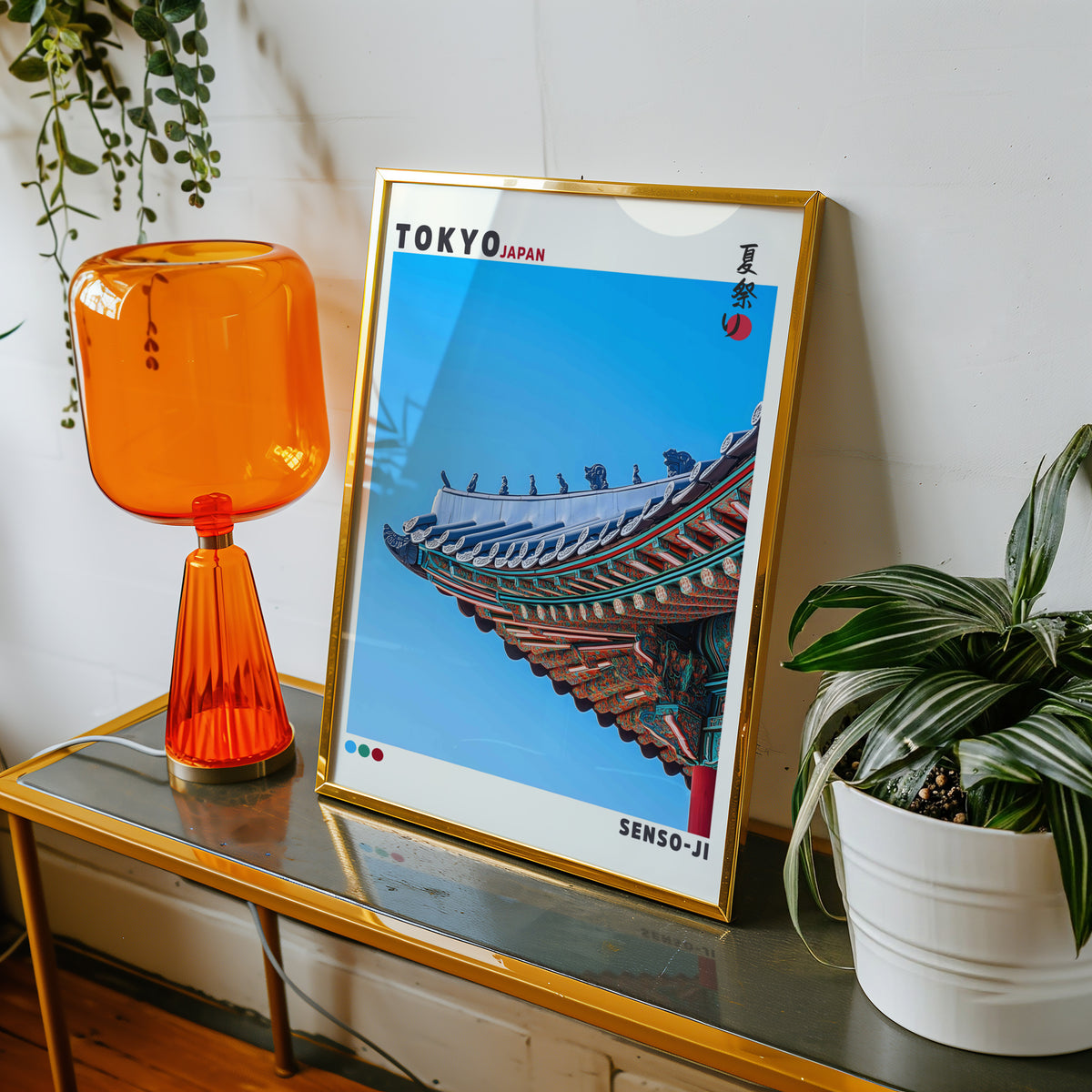 Senso-ji green temple roof detail print shown in a gold frame on a console beside an orange glass lamp