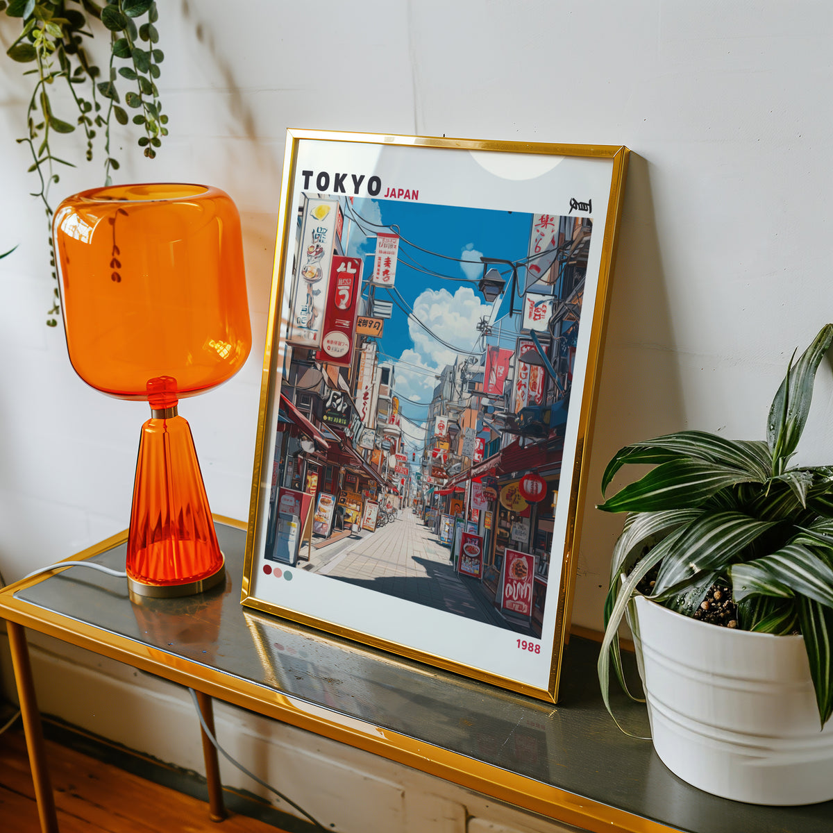 Tokyo shopping street 1988 print shown in a gold frame on a console beside an orange glass lamp