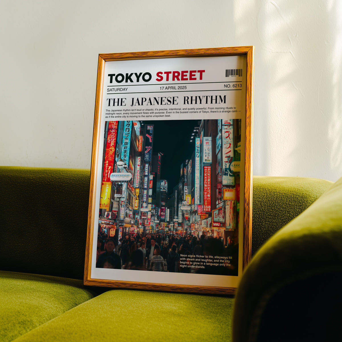 Tokyo street neon newspaper print in an oak frame propped on a green velvet sofa