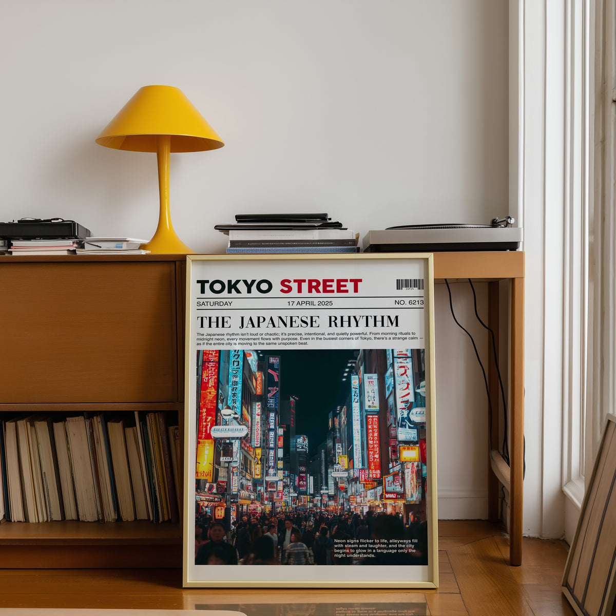Tokyo street neon newspaper print shown in a gold frame below a teak desk with a yellow lamp