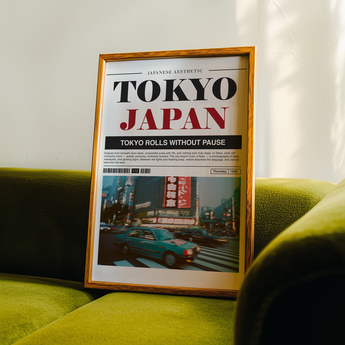 Tokyo taxi magazine layout print in an oak frame propped on a green velvet sofa