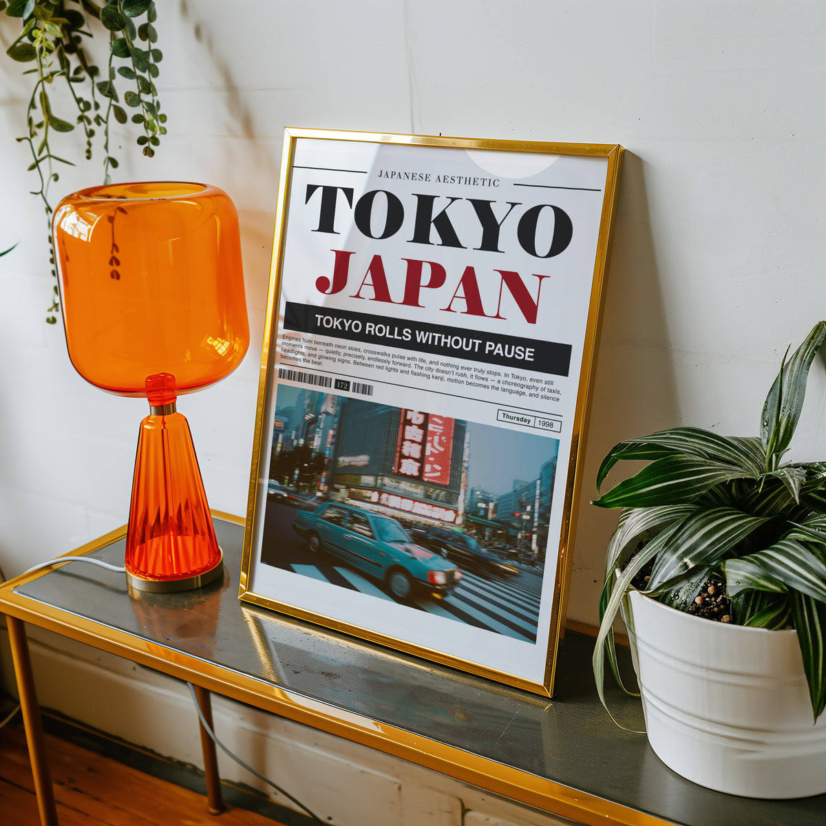 Tokyo taxi magazine layout print shown in a gold frame on a console beside an orange glass lamp