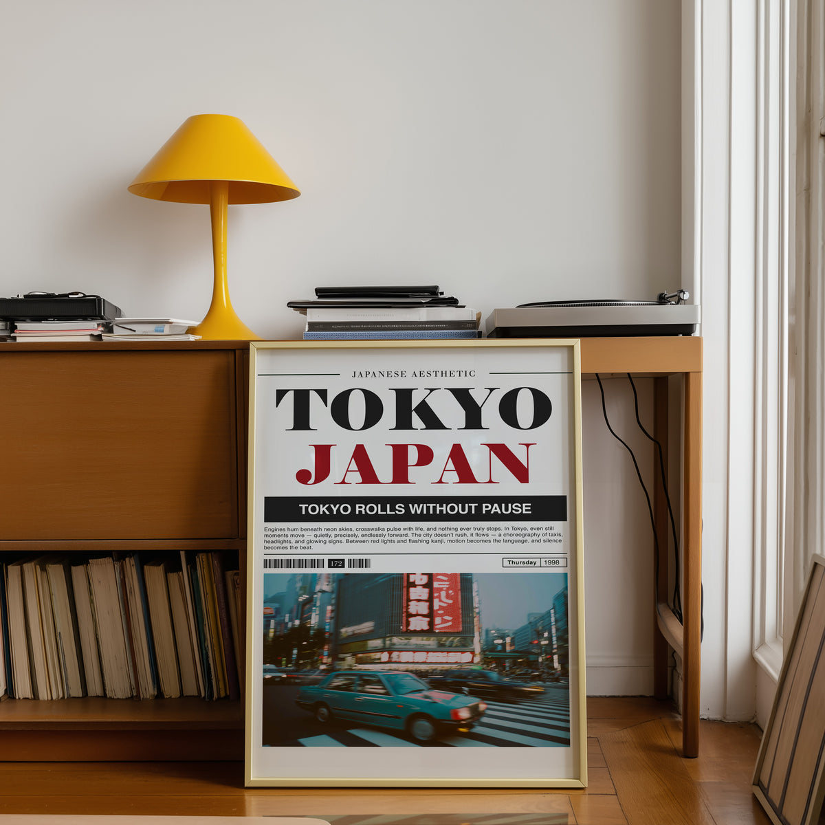 Tokyo taxi magazine layout print shown in a gold frame below a teak desk with a yellow lamp