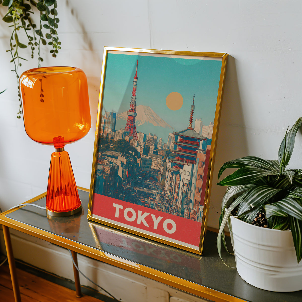 Retro Tokyo Tower and Mount Fuji print shown in a gold frame on a console beside an orange glass lamp