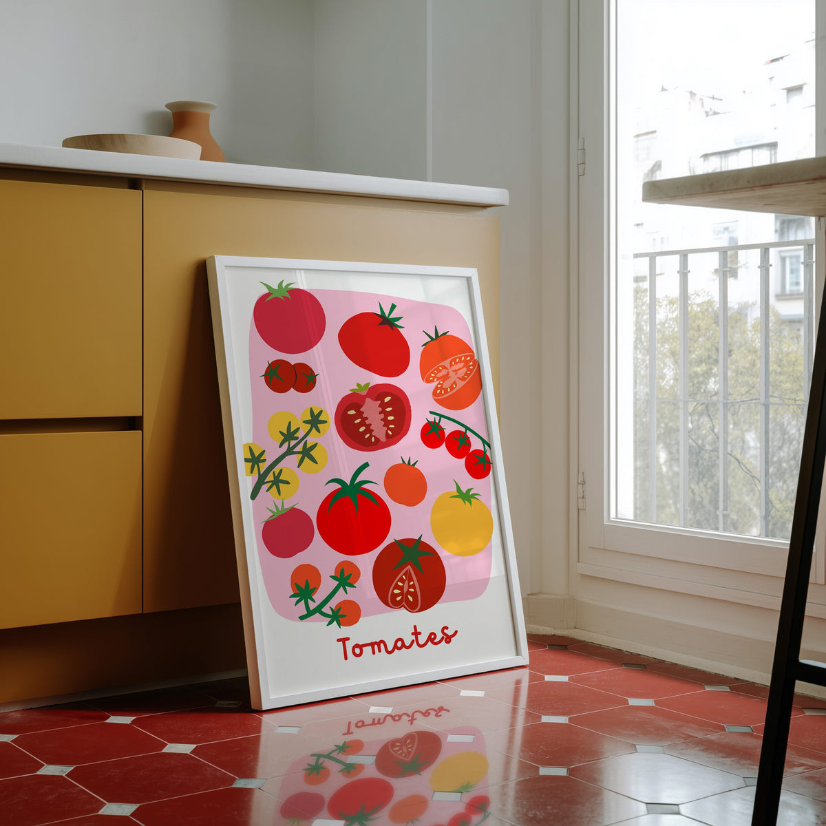 Tomates print in a white frame against yellow cabinets on a red tiled floor