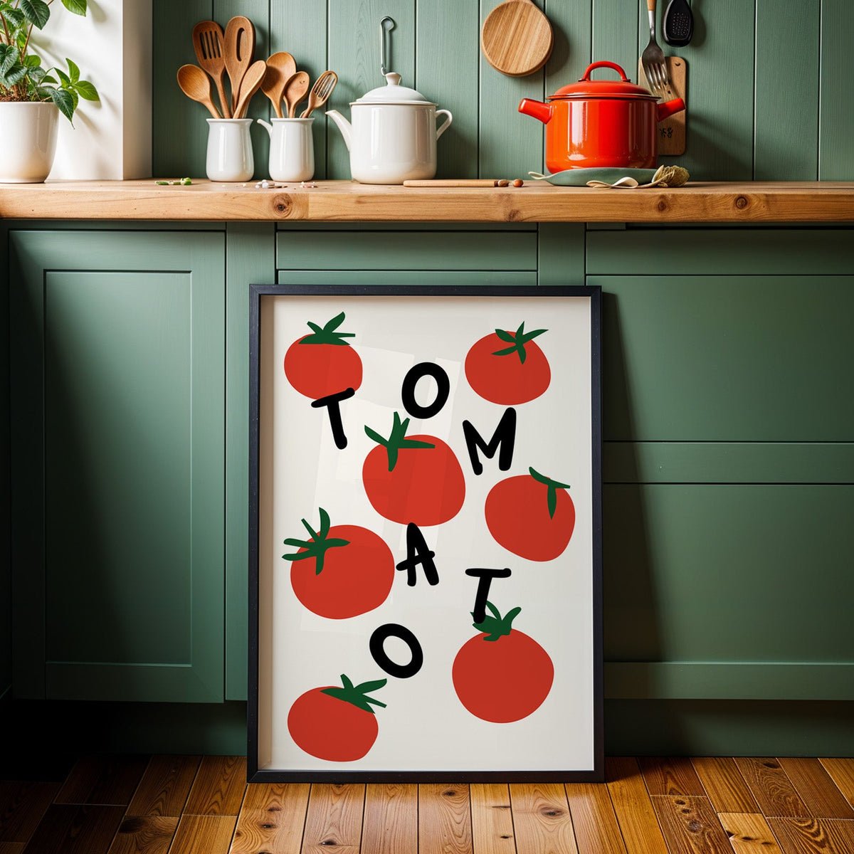 Tomato letters print in a black frame against sage green kitchen cabinets