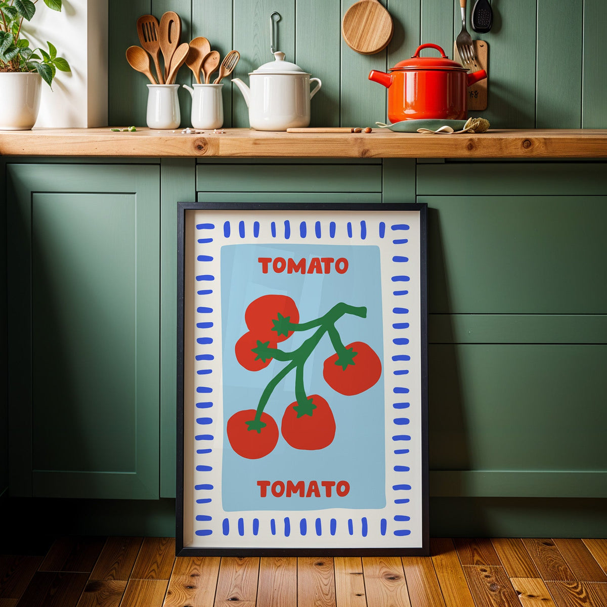 Tomato seed packet print in a black frame against sage green kitchen cabinets