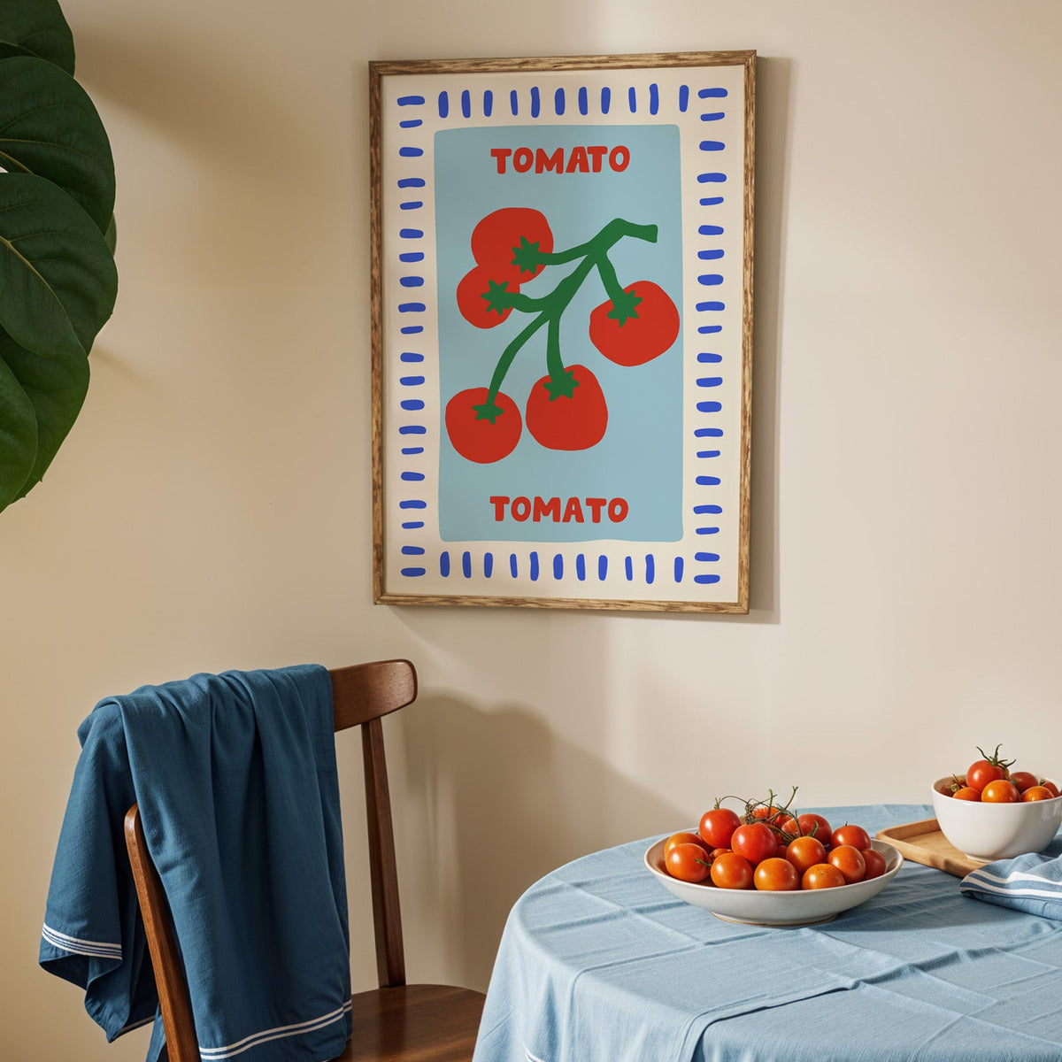 Tomato seed packet print in an oak frame above a blue linen table with ripe tomatoes